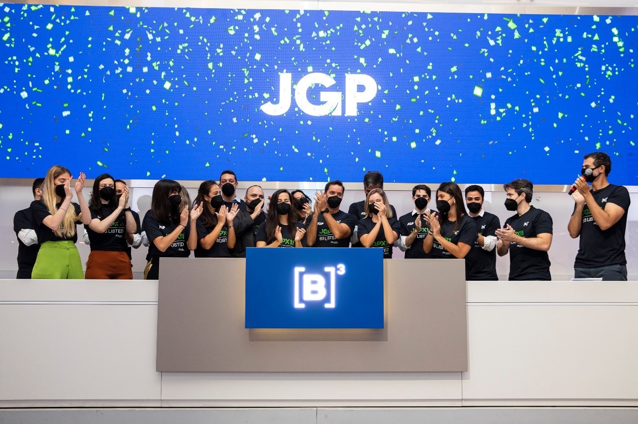 Grupo de pessoas bate palmas atrás do púlpito da B3 após toque de campainha em comemoração ao lançamento do fundo.