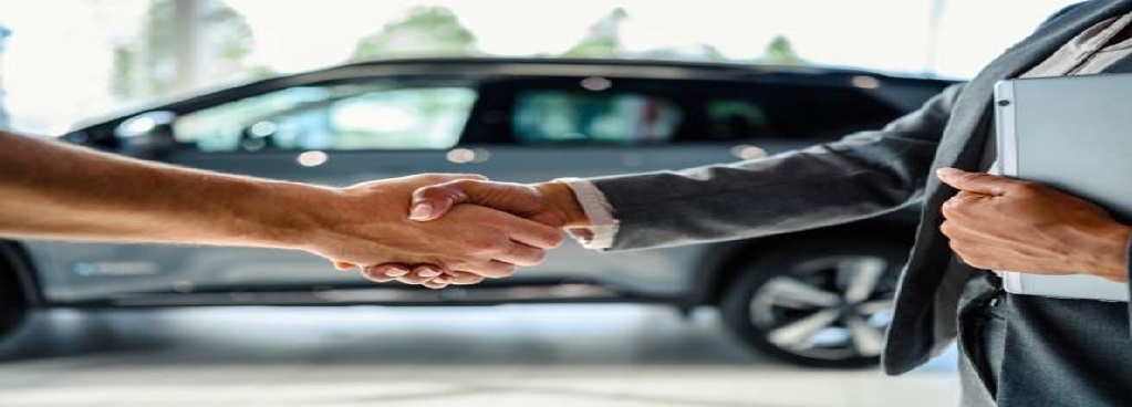 Duas pessoas se cumprimentando, ao fundo um carro desfocado