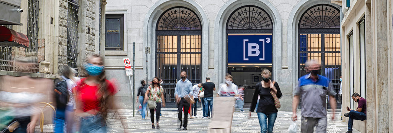 Fachada da B3 na rua XV de Novembro, com pessoas caminhando pela rua.