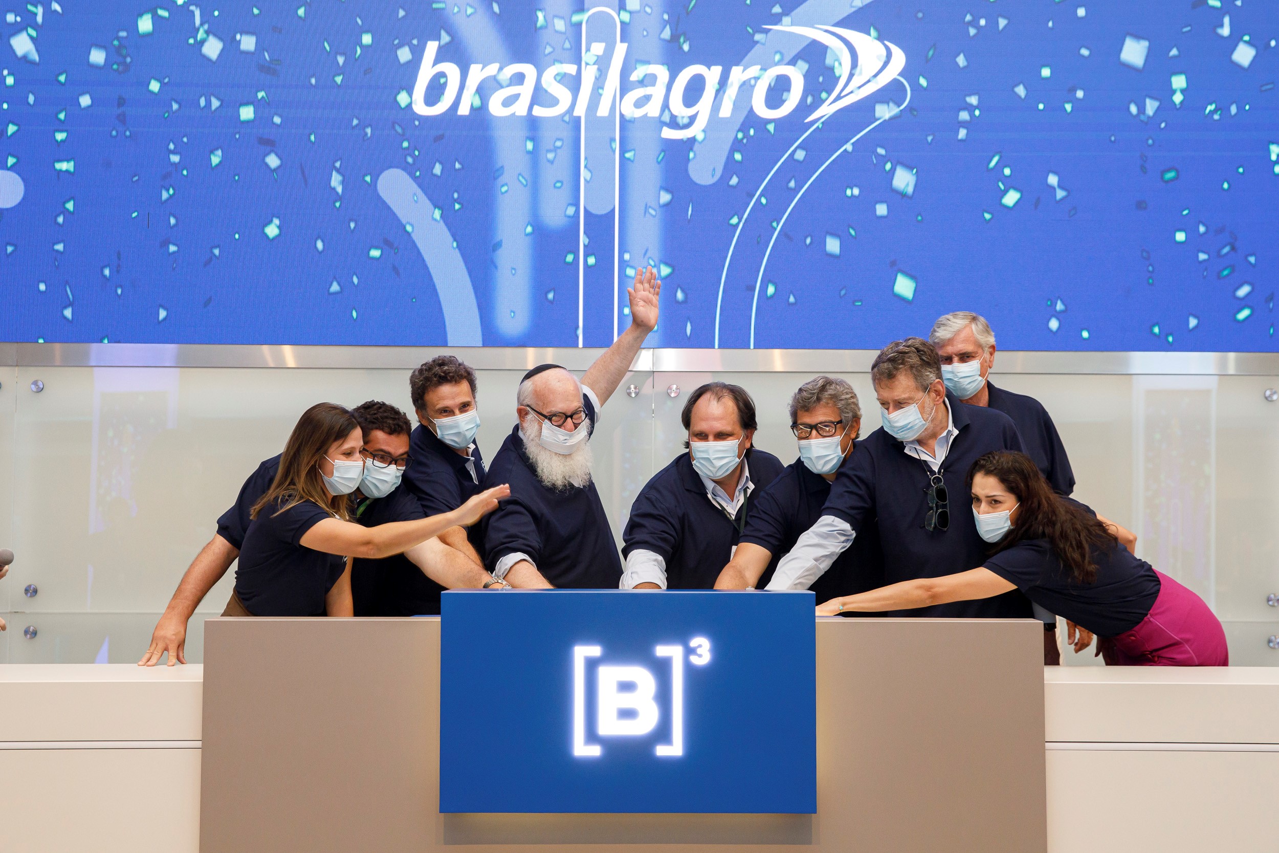 Grupo de pessoas toca a campainha em comemoração ao aniversário de listagem.