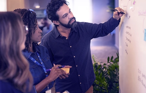 Three people collaborating in front of a whiteboard in an office environment